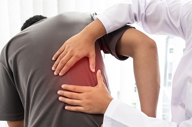 Médico y paciente en consulta, revisando dolor en la espalda